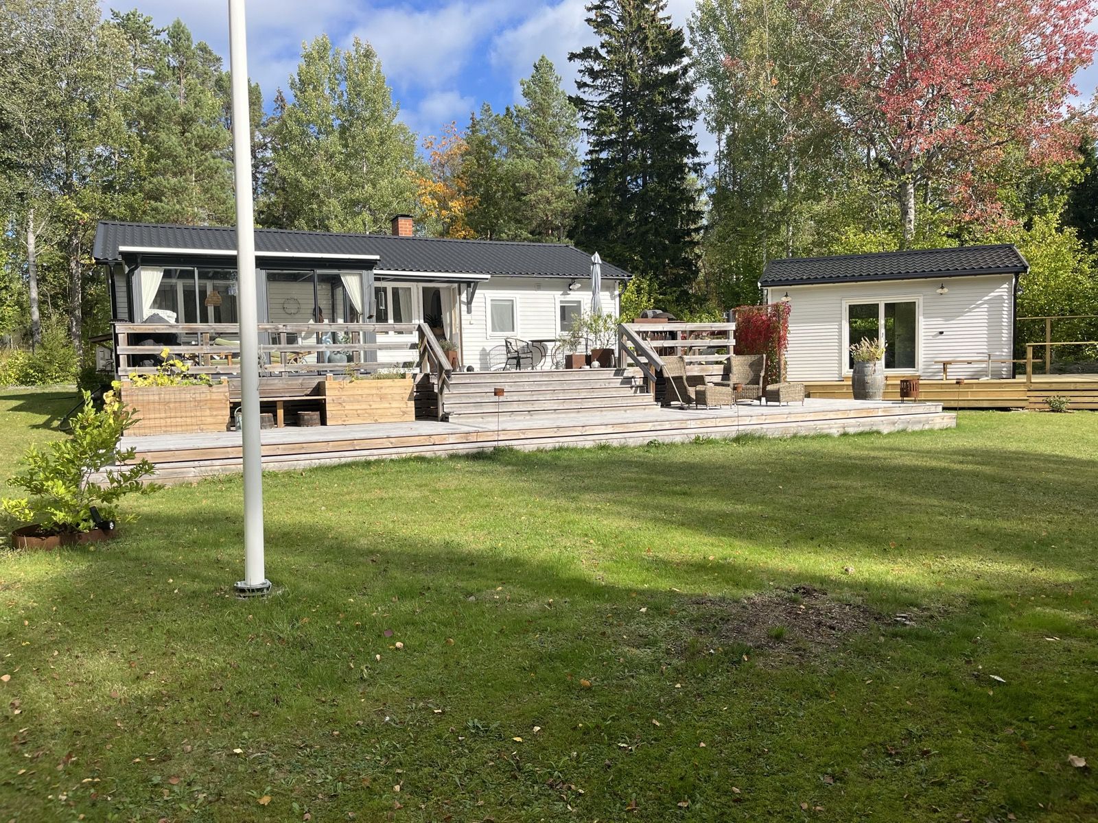 Det färdiga attefallshuset med altan, bredvid ett större hus