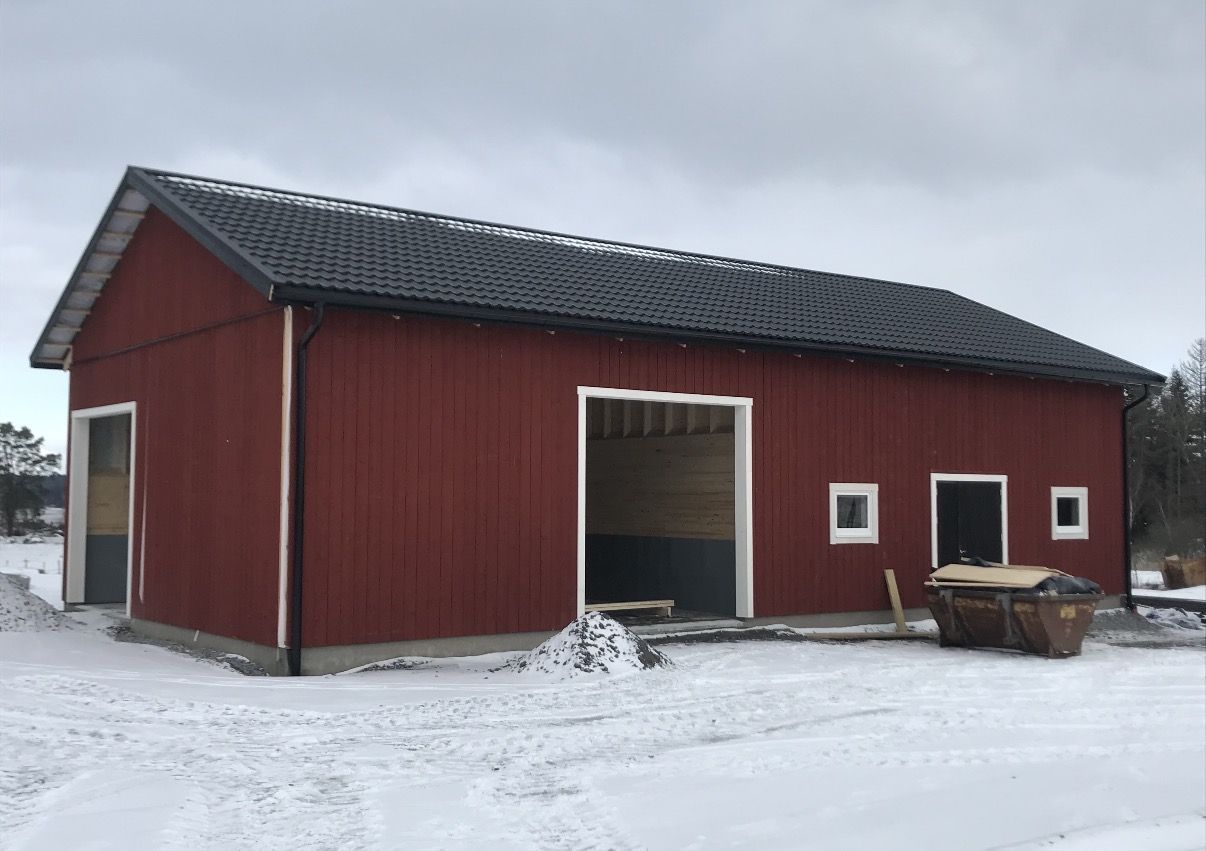Det färdiga stallet med svart tak i snö