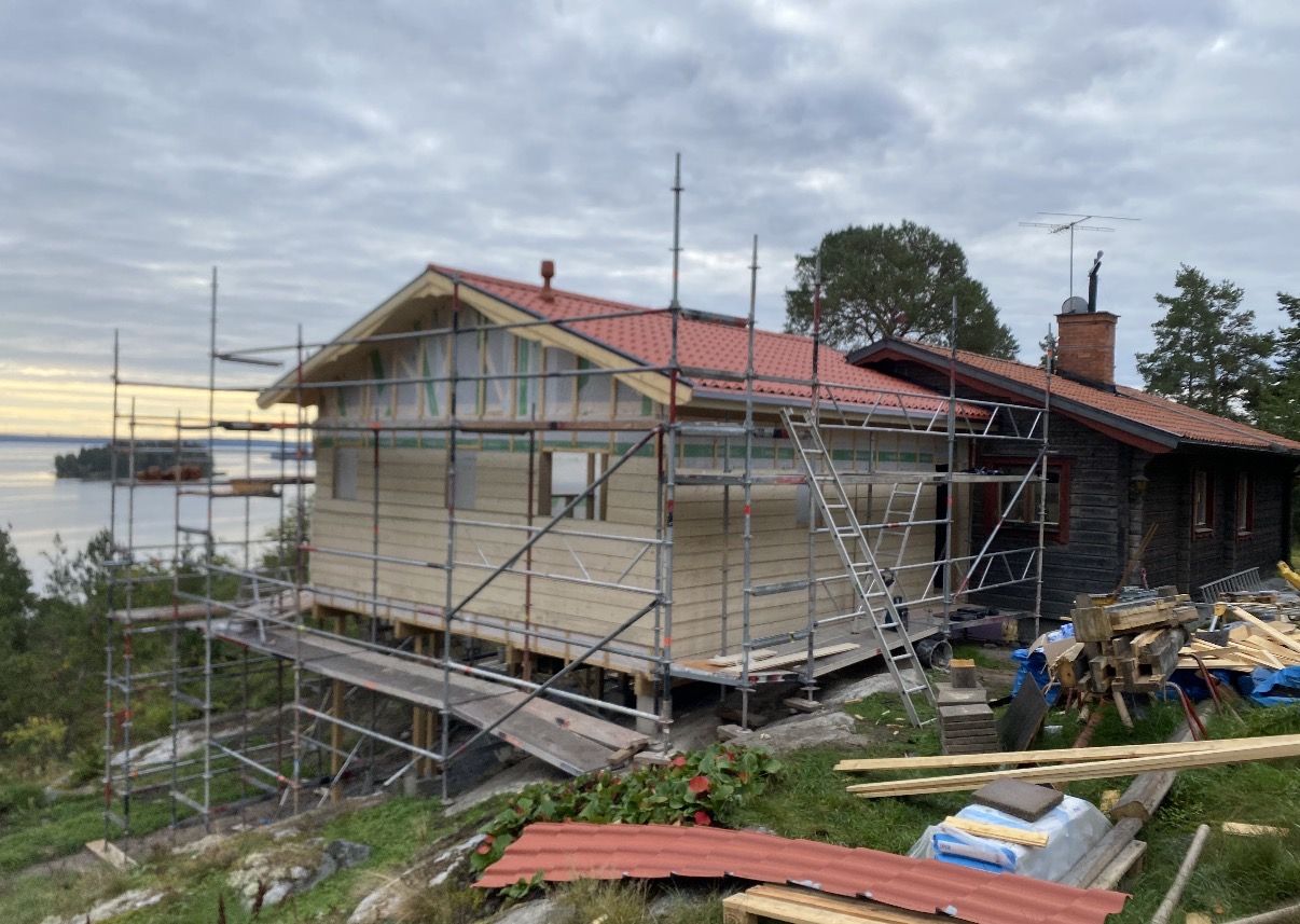 Tillbyggnaden med rött tak, intill timmerhuset
